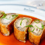 A plate topped with a roll covered in sauce.