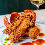 Fried seafood on a plate with a glass of wine.