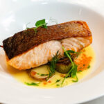 A white plate with a piece of fish on it.