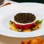 A white plate with a caviar on it.