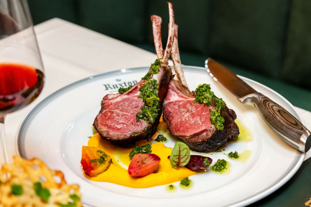 A plate with lamb chops and a glass of wine.